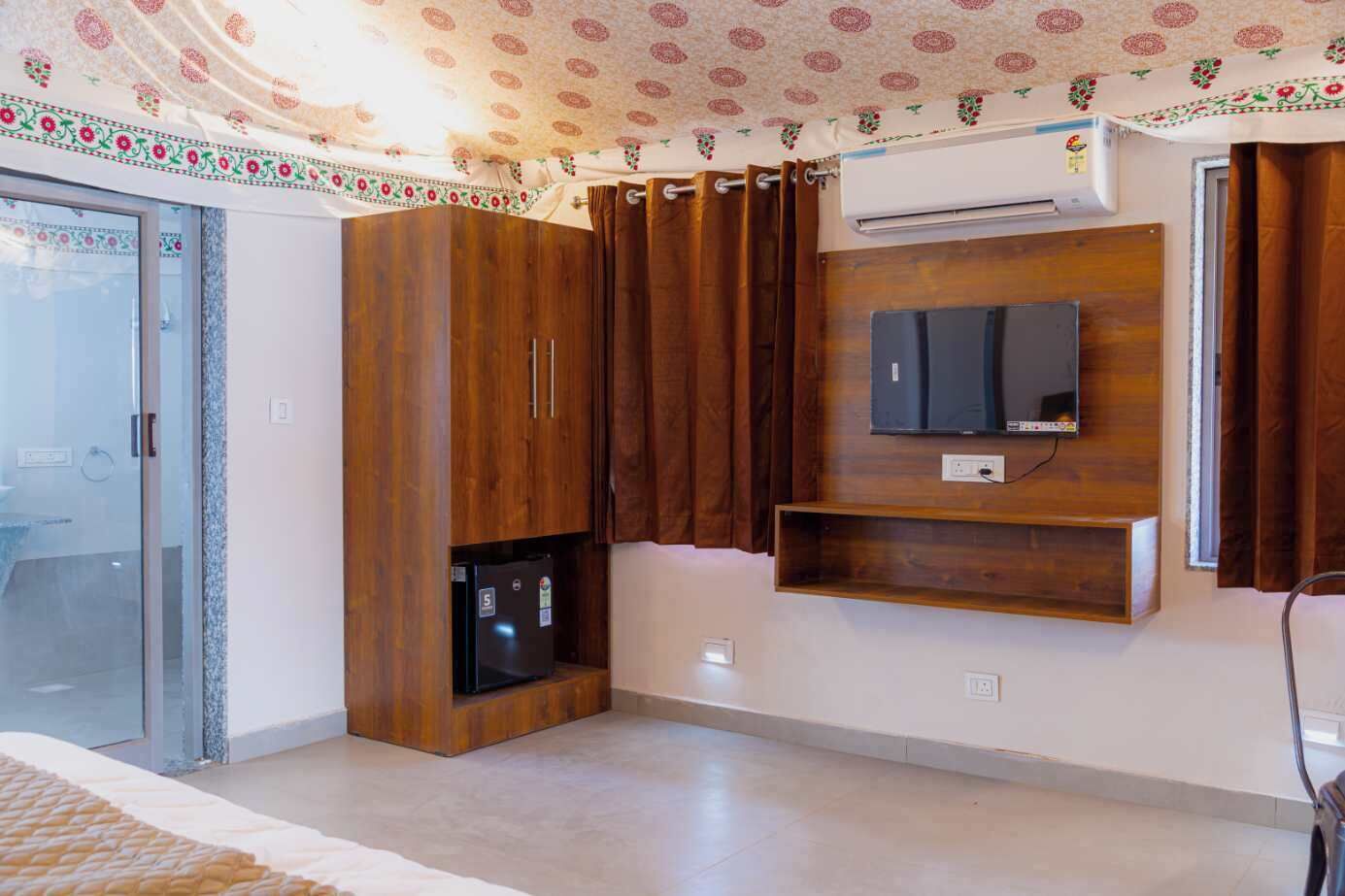 A room with a sliding glass door, a built-in wooden cabinet, a mounted TV, and an air conditioning unit.
