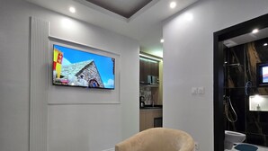 Un soggiorno moderno con una TV a schermo piatto montata a parete, una poltrona beige e un poggiapiedi nero.