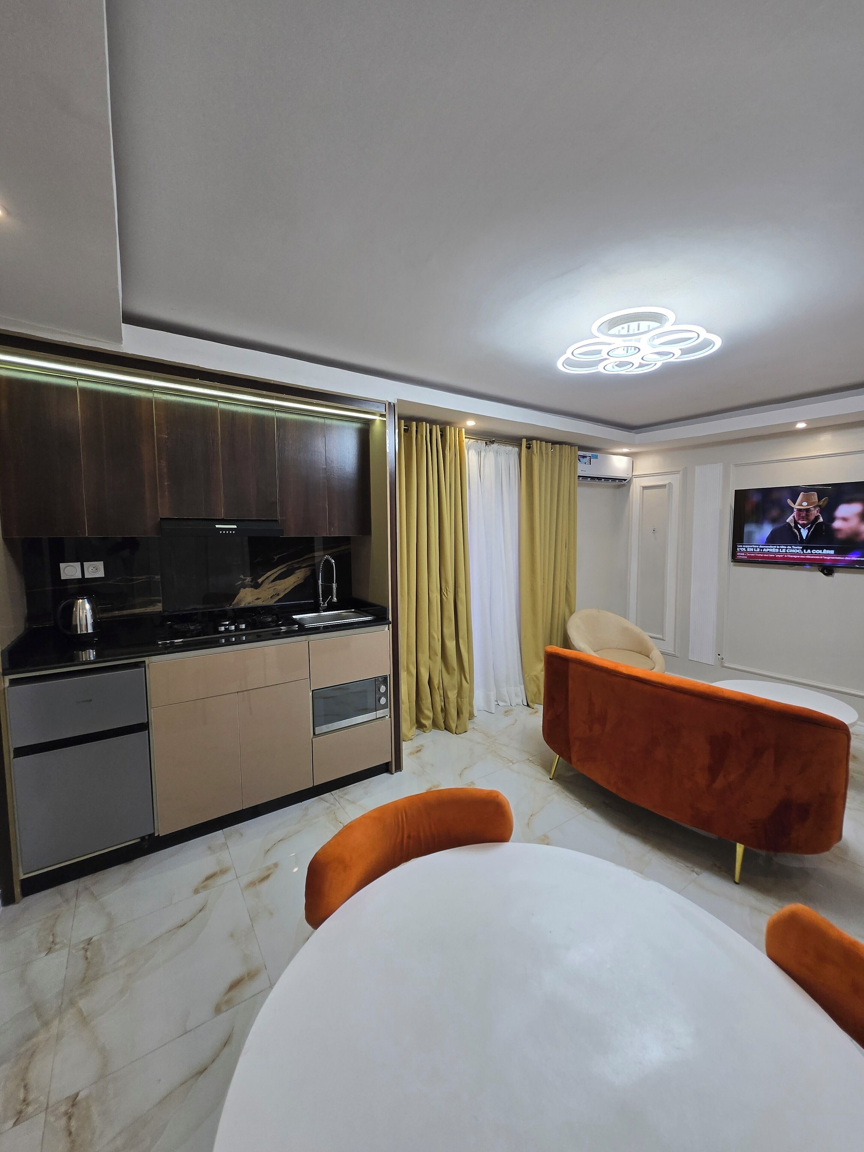 A modern kitchen with a built-in oven, a coffee maker, and a TV mounted on the wall.