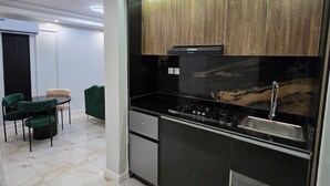 Una cucina moderna con mobili neri, un lavello in acciaio inossidabile e un piano di lavoro nero. C'è una zona pranzo con un tavolo rotondo e sedie.