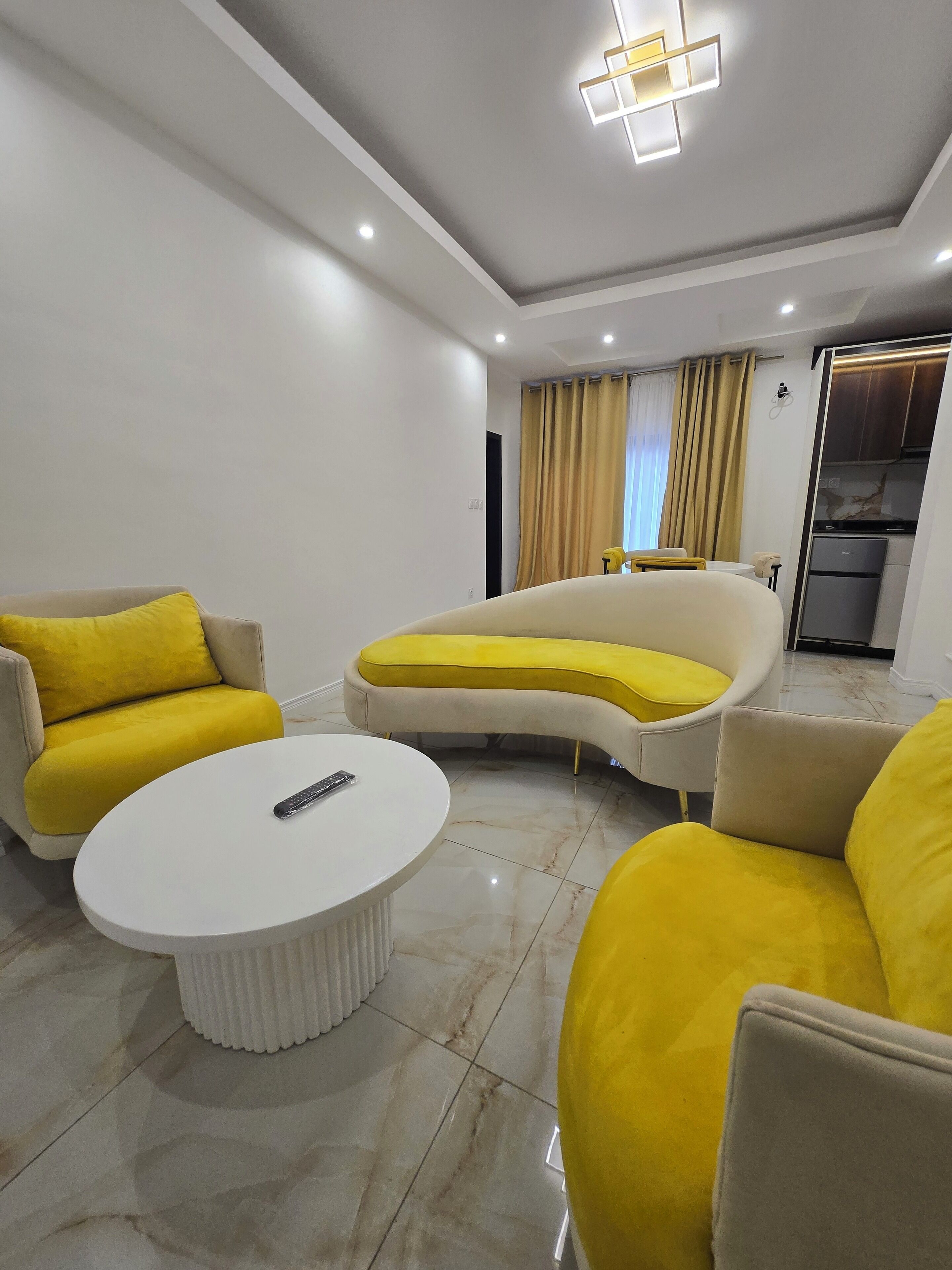 Un salon moderne avec un canapé blanc, des coussins jaunes et une table basse blanche.