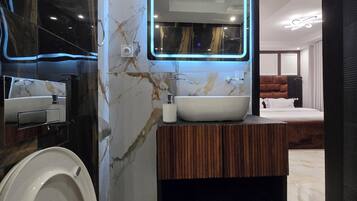 Une salle de bain moderne avec un mur en marbre, un lavabo encastré, des toilettes et un espace douche.