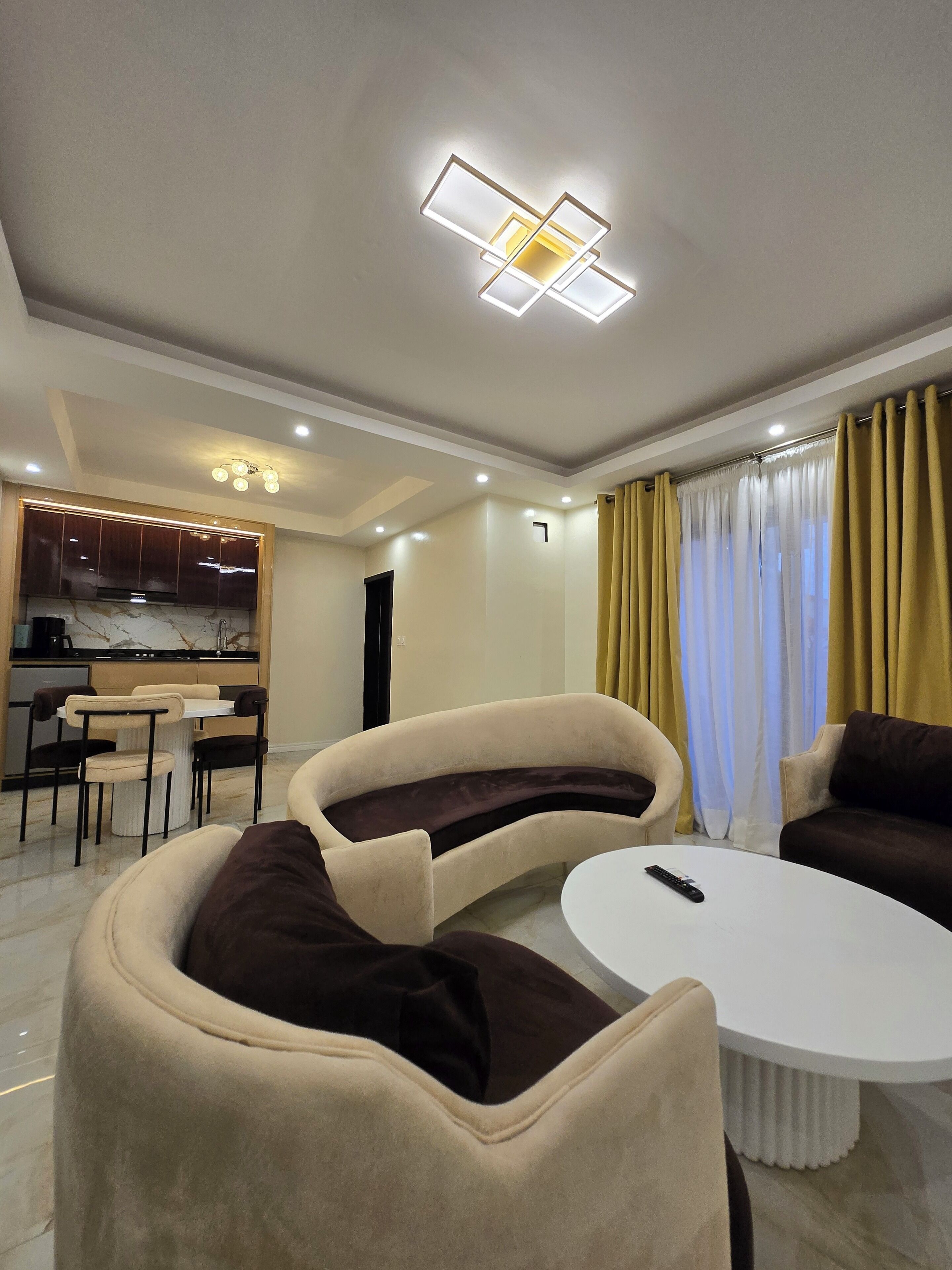 A modern living room with a sofa, a coffee table, and a kitchen area in the background.