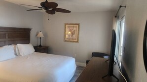 A hotel room with a bed, a nightstand, a lamp, a ceiling fan, a framed picture, and a television. - 1 Week ON VANDERBILT BEACH in Naples Florida. 
Oct 31-Nov 7 2026 ONLY (Naples)