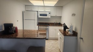 A compact kitchen with white cabinets, a microwave, a refrigerator, a coffee maker, and a sink. - 1 Week ON VANDERBILT BEACH in Naples Florida. 
Oct 31-Nov 7 2026 ONLY (Naples)