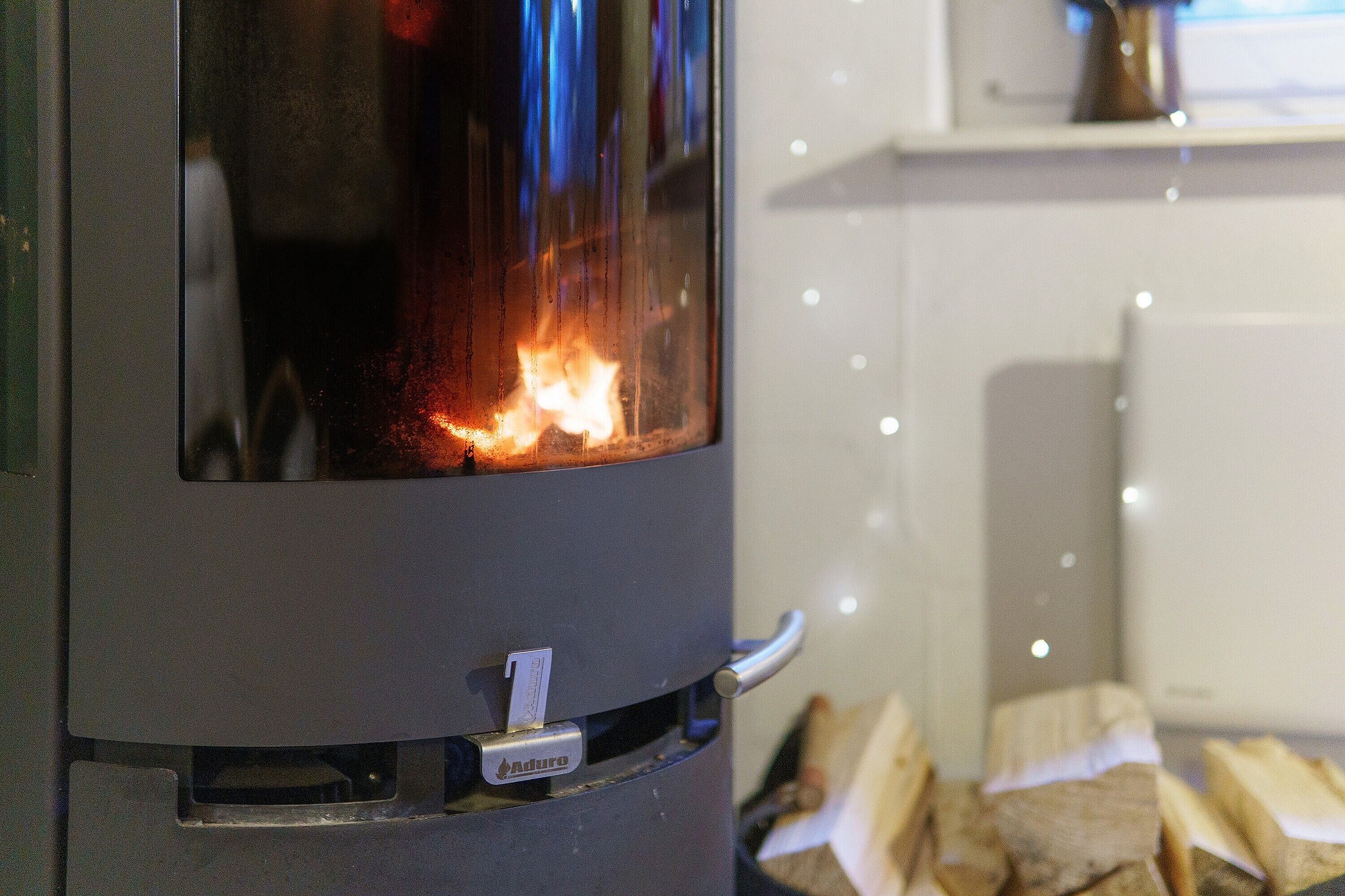 Un poêle à bois avec des flammes apparentes, une poignée en métal et une étiquette de marque.