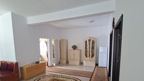 A spacious living area with a large rug, a sofa, a wooden cabinet, and a wardrobe.