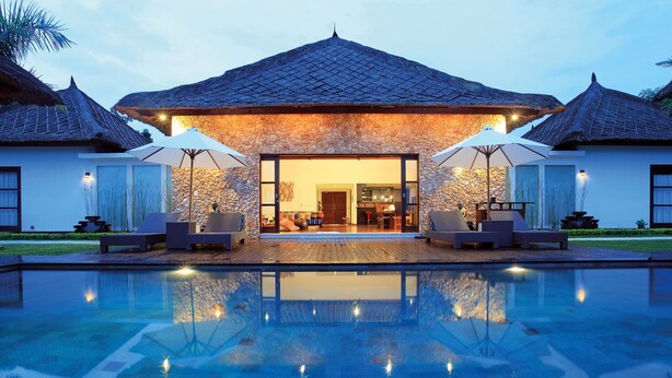 A resort with a swimming pool, a covered outdoor seating area, and a stone facade.