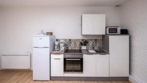 A compact kitchen with white cabinets, a microwave, a stove, and a small oven.