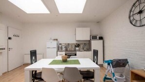 A compact kitchen with white cabinets, a microwave, and a dining area with a white table and chairs.