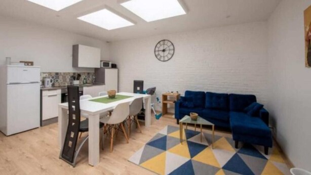 A compact living space with a kitchen, dining area, and a blue sofa.