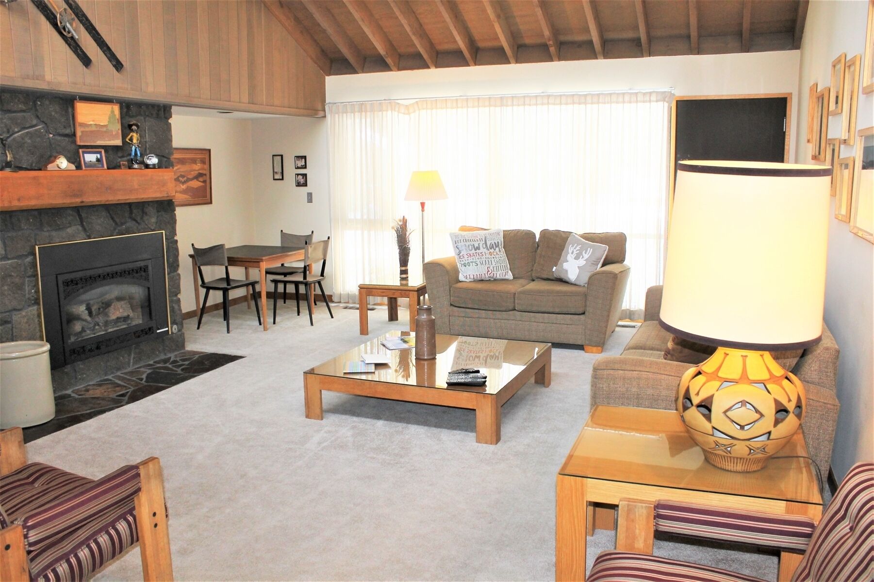 A cozy living room with a stone fireplace, a sofa, a coffee table, and a lamp.
