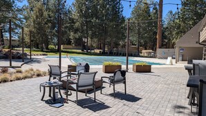 An outdoor patio with seating, a pool, and a view of trees.