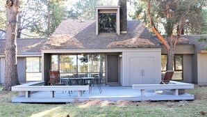 Une maison moderne dotée d’un patio couvert, d’un coin repas avec mobilier d’extérieur et d’une cheminée.