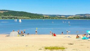A beach with people, boats, and a clear sky.