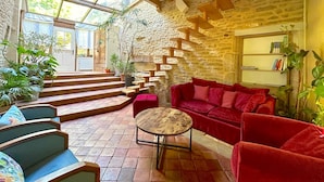 A cozy interior with a red sofa, a wooden coffee table, and a staircase against a stone wall.