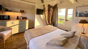 Quarto com cama, cadeira, televisão e vista para o exterior.