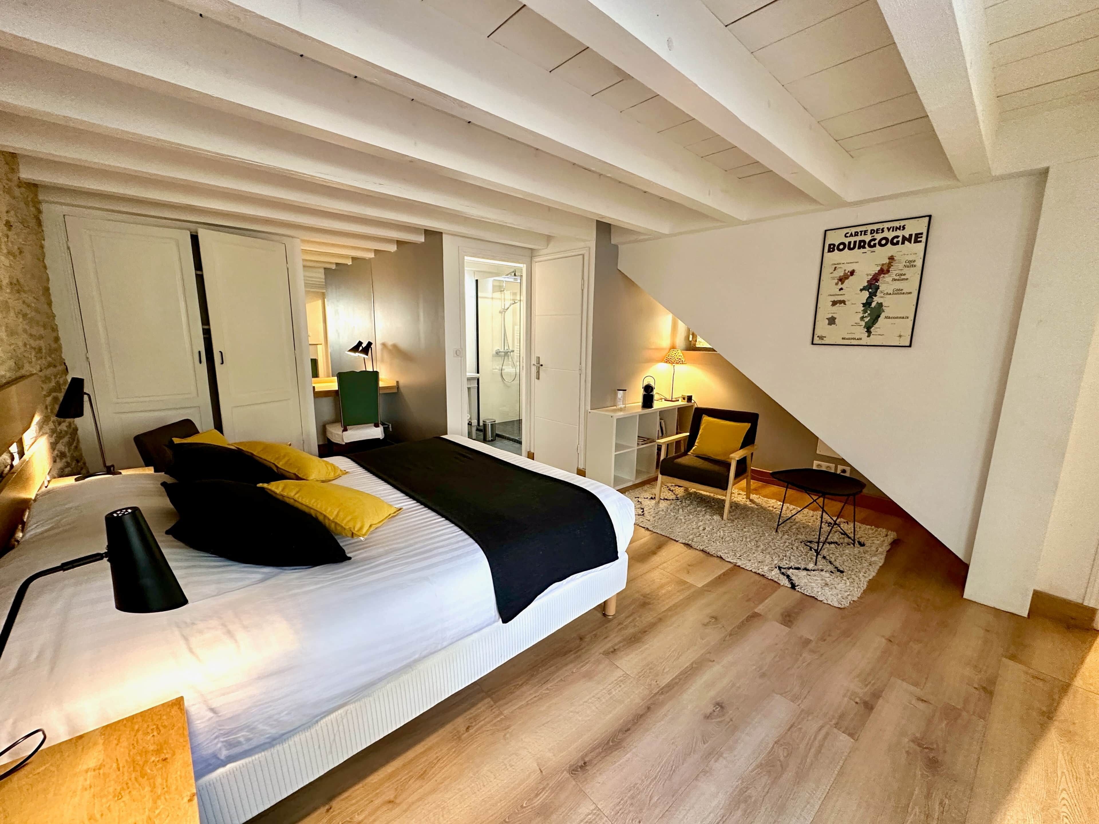 Une chambre à coucher avec un lit, une table de chevet, une lampe, une chaise et une carte accrochée au mur.