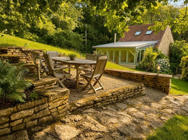 A patio with stone walls, a wooden table, and chairs.