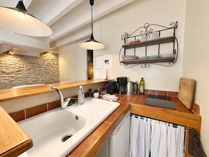 Una cocina con encimera de madera, un lavabo blanco, una cafetera y una lámpara colgante.