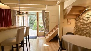 A dining area with a table and chairs, a staircase, and a view of the outdoors. - The Fleurières (Montoillot)