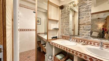 A bathroom with a stone wall, a large mirror, and a wooden vanity.