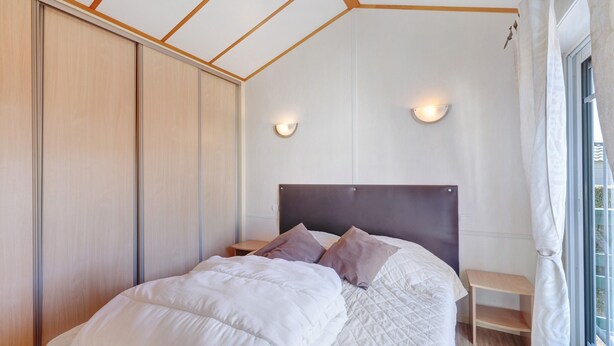 Une chambre à coucher avec un lit, des tables de chevet, une armoire et une fenêtre avec des rideaux.