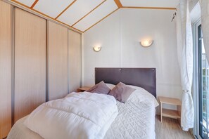 Une chambre à coucher avec un lit, des tables de chevet, une armoire et une fenêtre avec des rideaux.