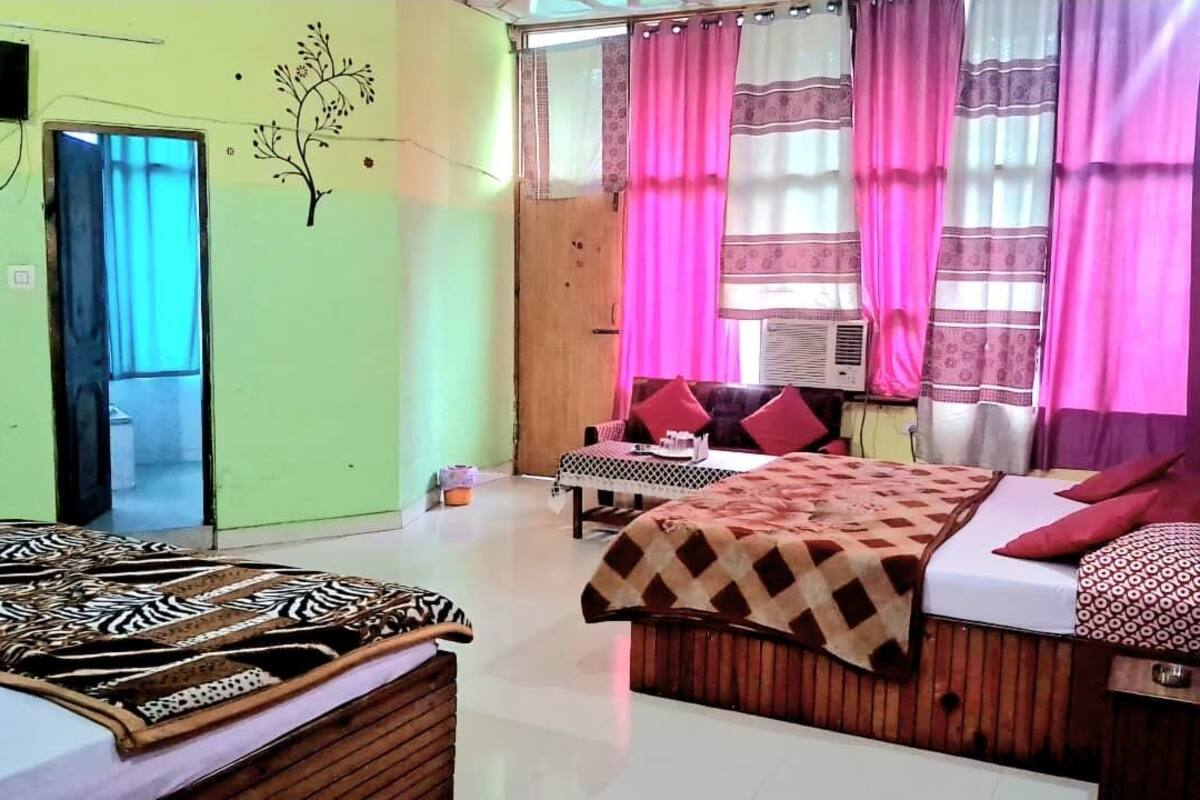 A room with a bed, a wooden headboard, a small table, and a window with curtains.