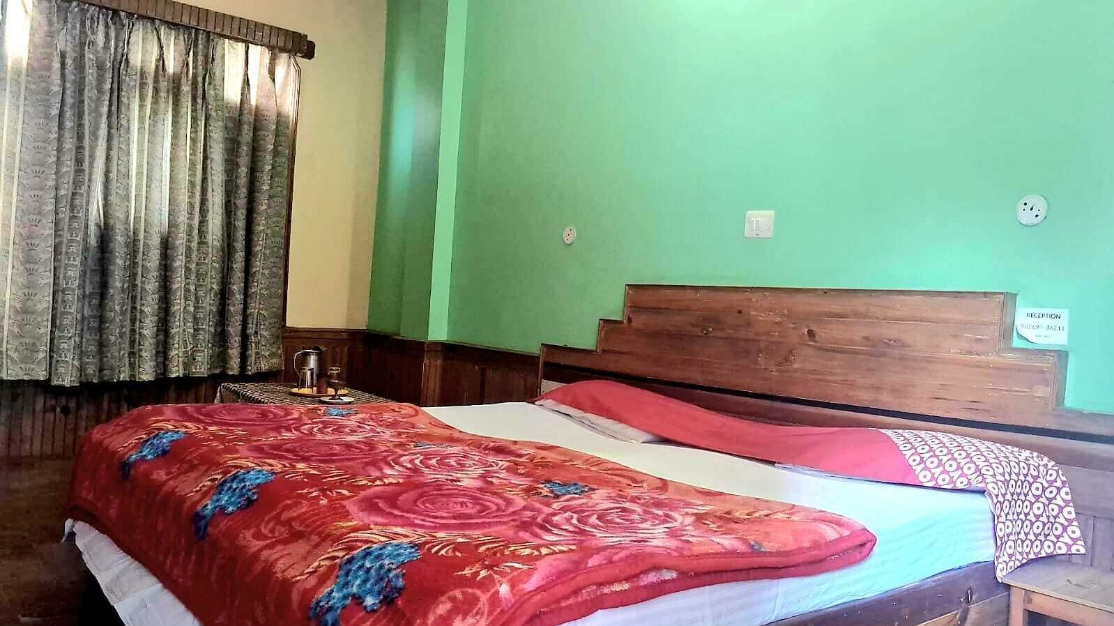 Una habitación con una cama, cabecera de madera, pared verde y un letrero de recepción.