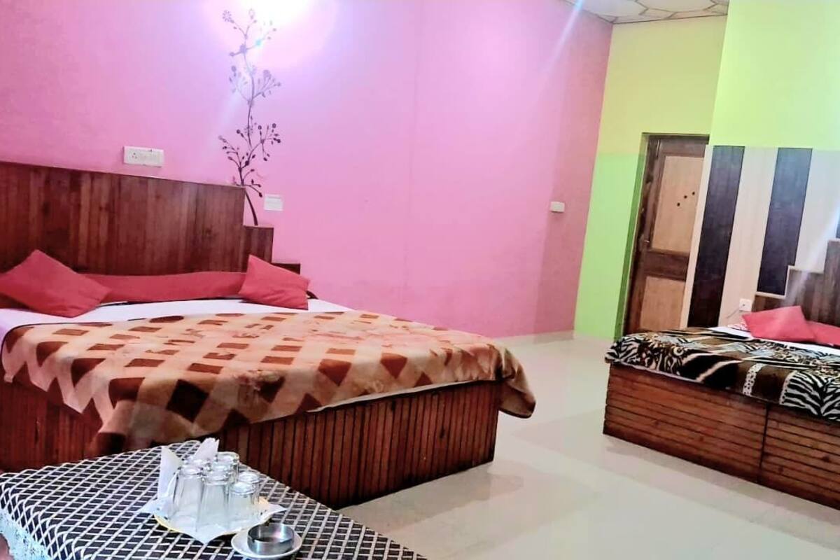 A hotel room with a wooden bed, a sofa, and a small table with glasses and a plate.