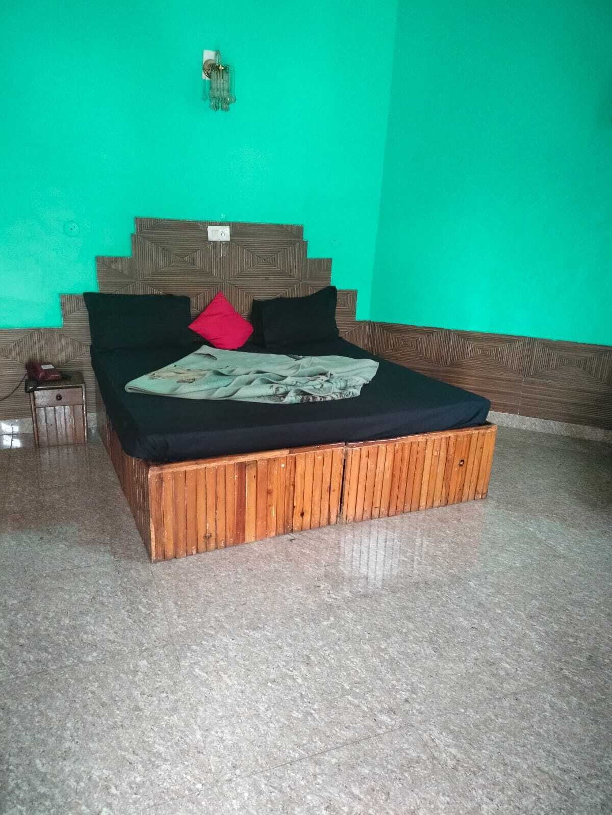 Una cama con estructura de madera y pared verde.