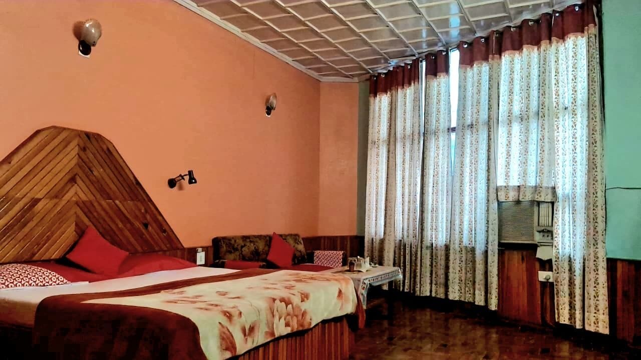 Una habitación con cama, sofá, mesa y cortinas.