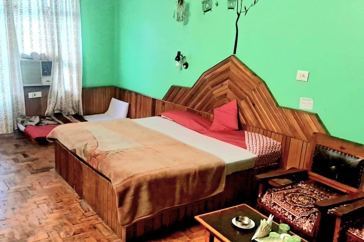 A room with a wooden bed, a small table with a tray, a chair, and a shelf with decorative items.