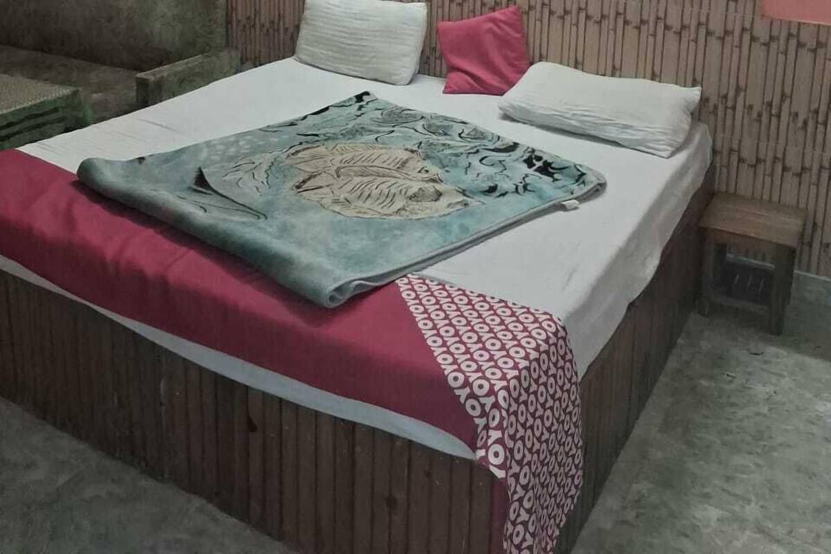 A bedroom with a bed, a ceiling fan, a nightstand, and a wall-mounted light fixture.