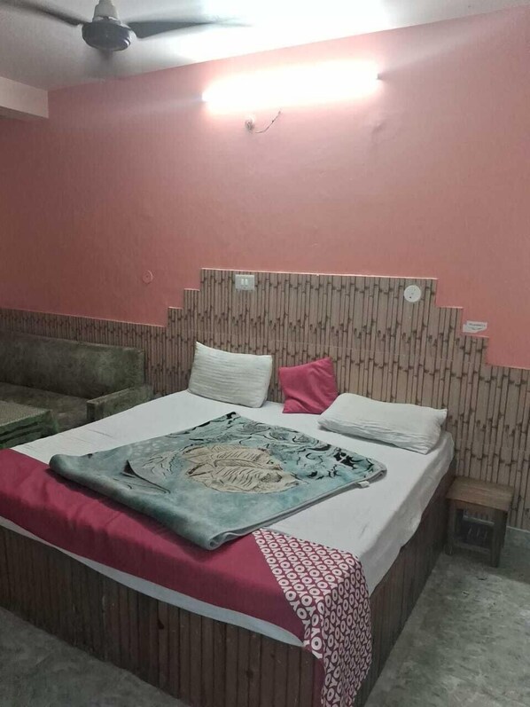 Un dormitorio con cama, ventilador de techo, mesita de noche y lámpara de pared.