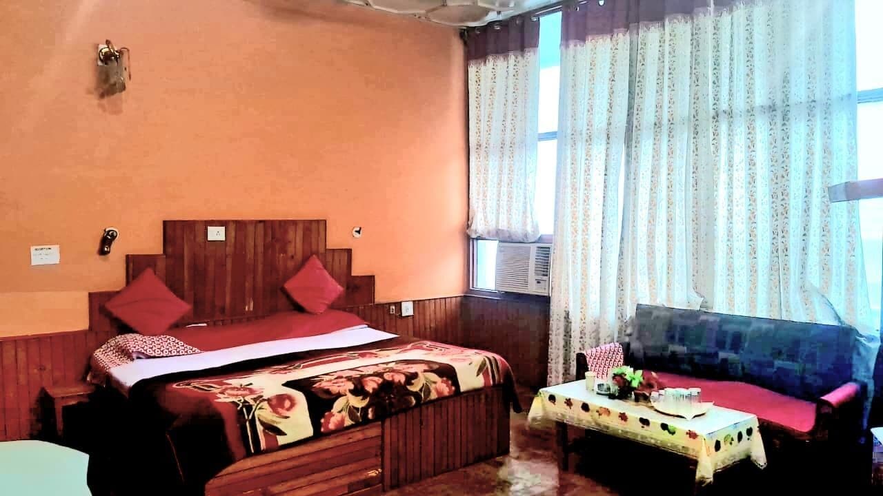Una habitación con una cama de madera, un sofá y una pequeña mesa con mantel.