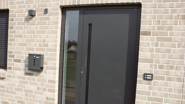 A modern building with a large black door, a small window, and a brick wall. - Stylish living - job & vacation (Soltau)