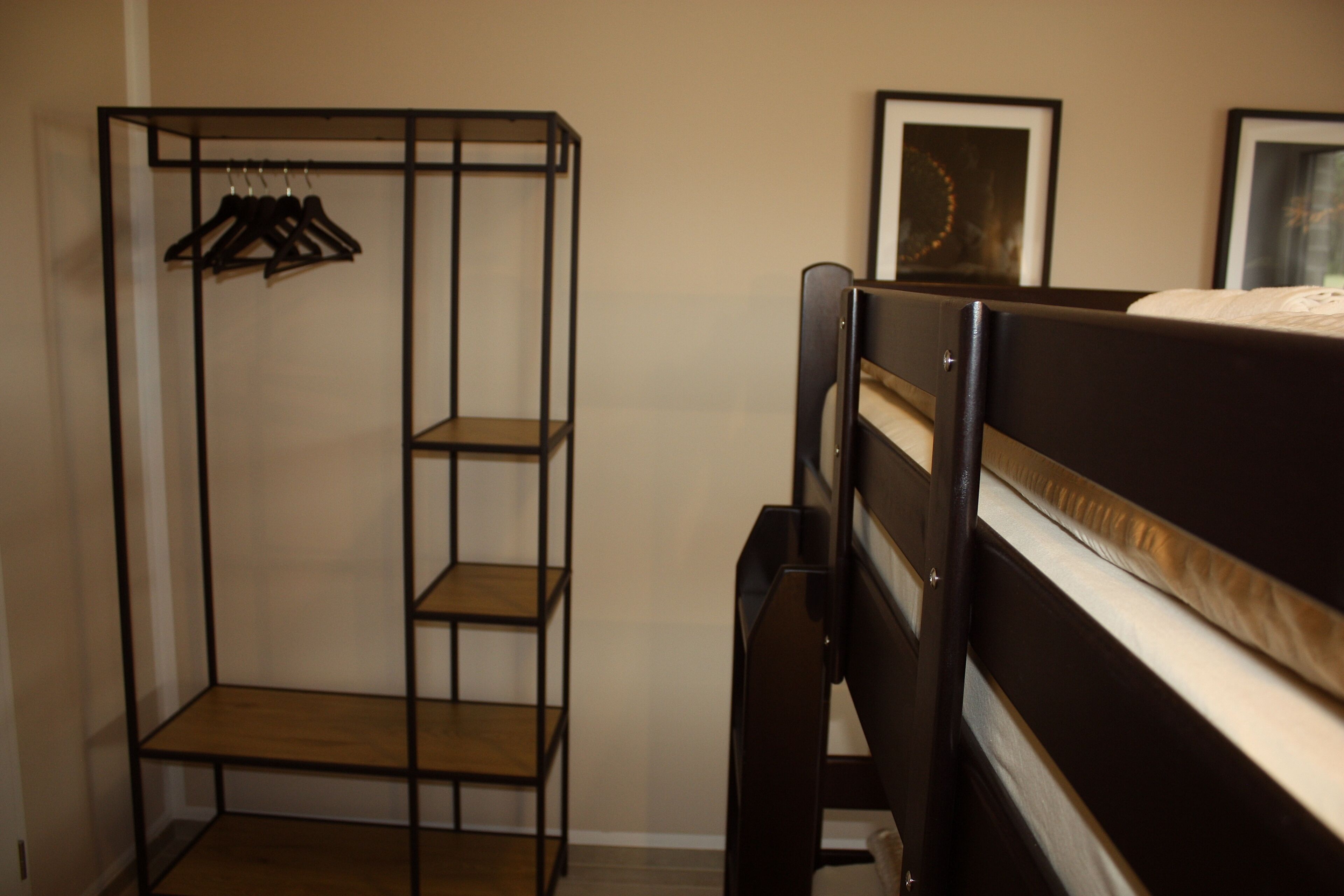 Una cama litera con estructura de madera y un armario metálico con estantes.