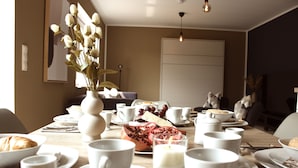 A dining table set with white plates, cups, and a vase of flowers. - Stylish living - job & vacation (Soltau)