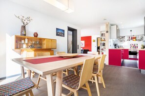 Una cocina moderna con comedor, muebles de madera y una pared de acento roja.