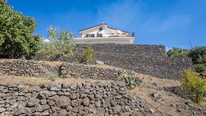 A house with a stone wall, a balcony, and a clear blue sky.