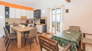A compact kitchen with modern appliances, a dining area with a wooden table and chairs, and a balcony with a view.