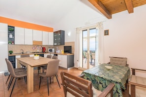A compact kitchen with modern appliances, a dining area with a wooden table and chairs, and a balcony with a view.