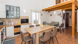 A compact kitchen with modern appliances, a dining area with a wooden table and chairs, and a balcony with a wooden railing.