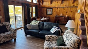 A cozy cabin interior with a wooden interior, a dining area, and a staircase. - Riverfront 2-bedroom house tons of light, AC, deck & patio Sleeps 8 Pet Friendly (Fort Edward)