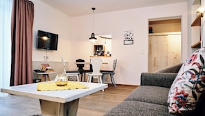 Een moderne woonkamer met een bank, een salontafel, een televisie en een eethoek met stoelen en een tafel.