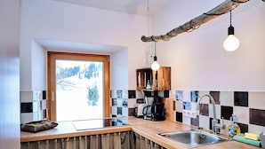 Een keuken met een houten aanrecht, een spoelbak, een koffiezetapparaat en een hangende lamp.