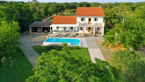 A two-story house with a swimming pool, a covered patio, and a garage with two cars.