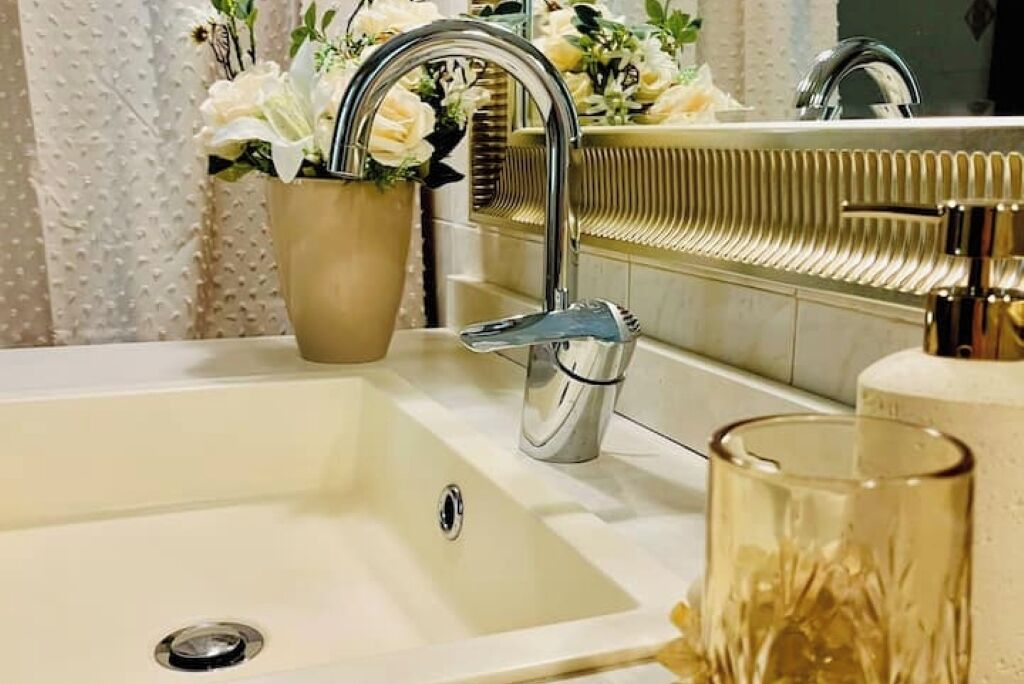 A bathroom with a sink, a mirror, and a potted plant.